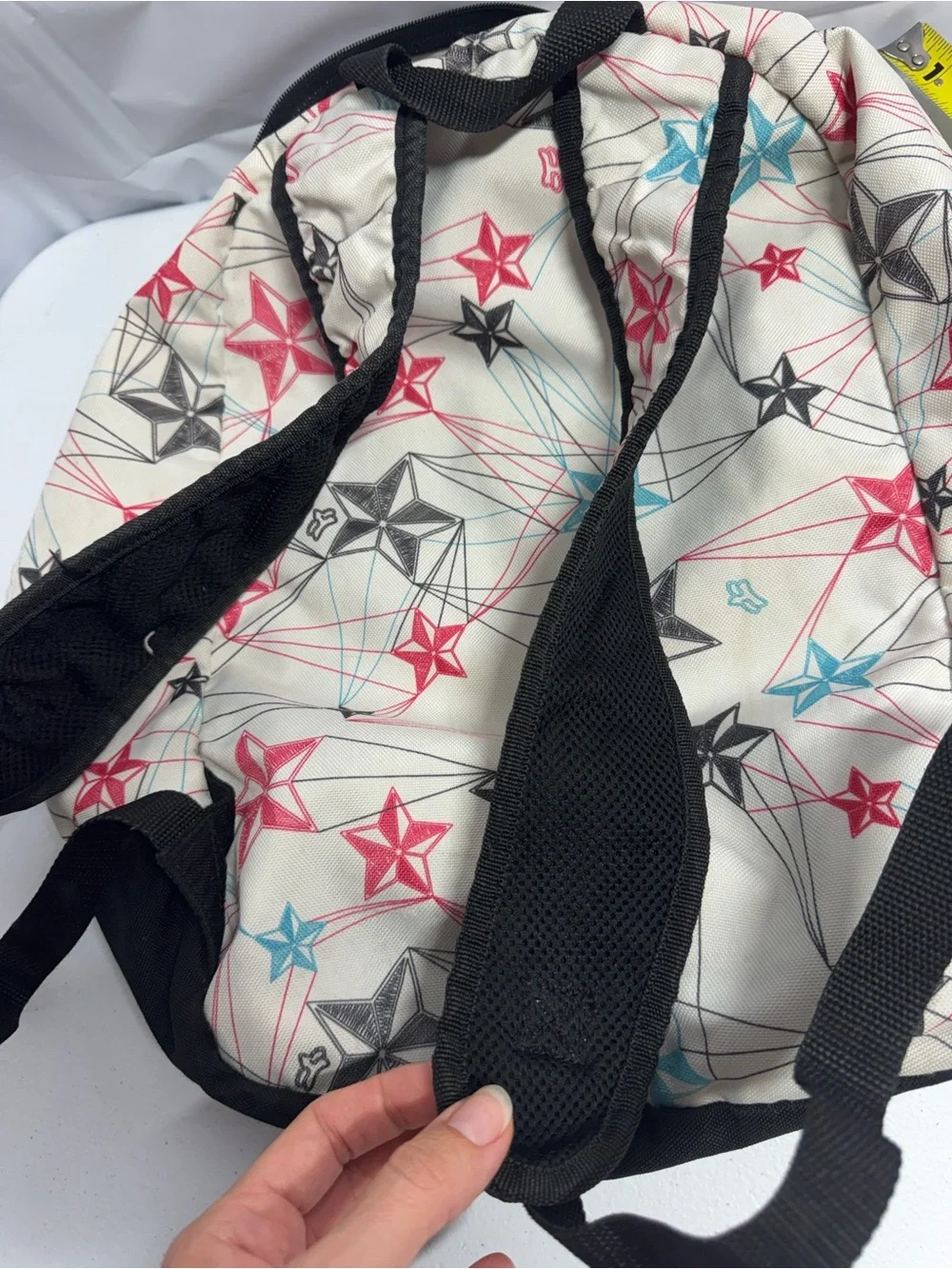 Fox Racing white polyester backpack with red, blue, and black stars and lines